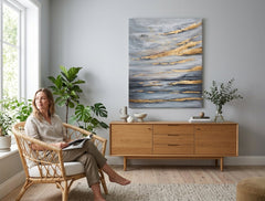 Ο χειροποίητος πίνακας Ουρανός 90x110 cm, με γκρι-μπλε και χρυσές αποχρώσεις, κοσμεί ένα μοντέρνο σαλόνι, προσδίδοντας ηρεμία και πολυτέλεια στον χώρο.